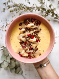 Smoothie Bowl mit Sanddornsaft in einer Hand gehalten