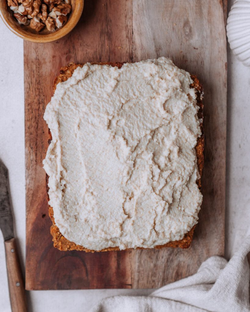 gebackener Carrot Cake von oben mit weißer Creme auf einem Holzbrettchen