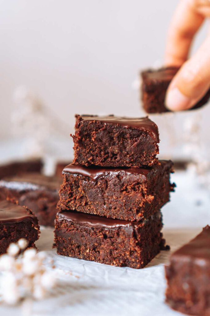 Turm aus 3 Schokoladenbrownies mit einer Hand im Hintergrund