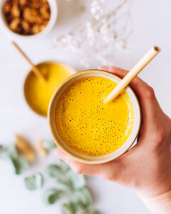 2 Tassen Kurkuma Latte (Goldene Milch) in einer Hand gehalten